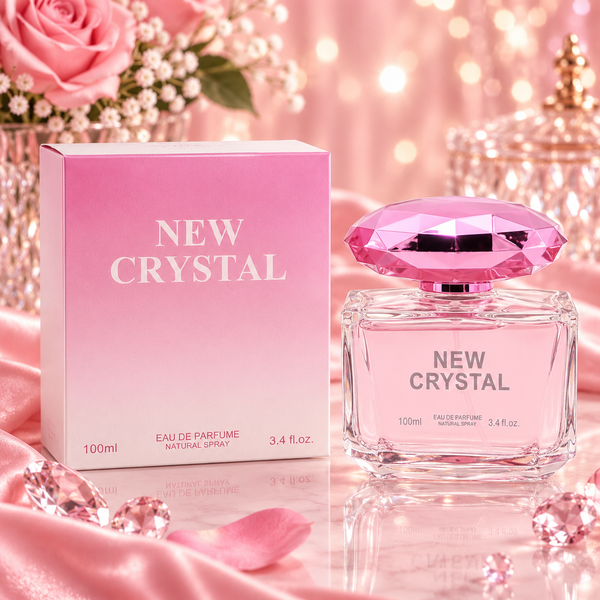 New Crystal Eau de Parfum bottle and its pink gradient box, styled with pink satin fabric, rose petals, and a pink rose in the background.